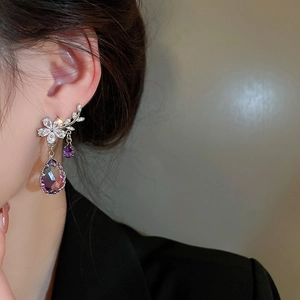 Detail shot of branch-shaped silver earrings with purple crystal pendants on model