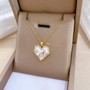 Macro shot of gold heart pendant with white enamel and zircons in a jewelry box