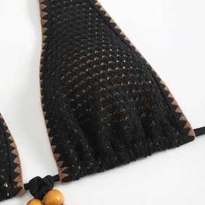Detailed macro view of black crochet bikini top with bohemian embroidery and wooden beads