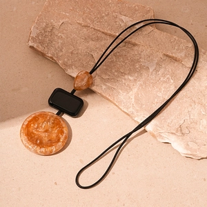 Detail of the amber resin pendant with black rectangular block on a long sweater necklace