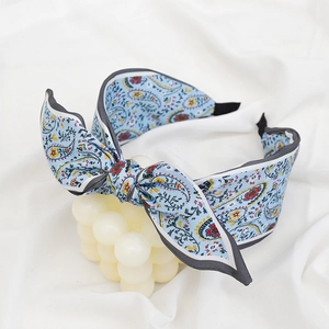 Detail of light blue paisley bow headband on white fabric with bubble decorations