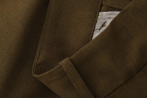 Gros plan du pantalon plissé vert olive montrant la texture du tissu et la couture