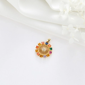 Vue détaillée du pendentif roue solaire dorée avec zircons colorés sur tissu blanc lisse