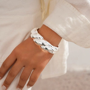 Close-up of a chunky silver twisted cuff bracelet with high-polish metallic texture