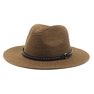 Detail of a brown straw fedora with black ribbon featuring gold metallic studs