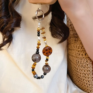 Close-up of vintage acrylic beaded phone charm featuring amber and tortoise shell beads