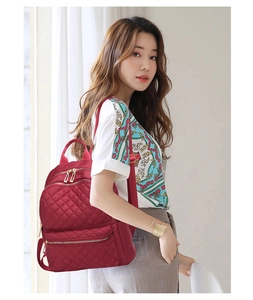 Quilted burgundy oxford backpack shown on model with adjustable straps and metal zippers
