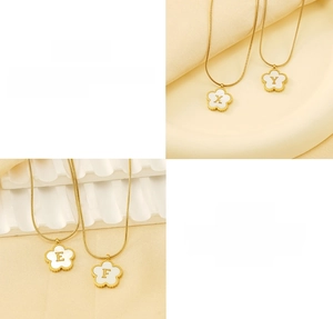 Macro detail of 18K gold-plated clover pendant with white shell and engraved initials