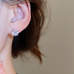 Detailed close-up of sparkling zircon round stud earrings with 4-claw setting on ear