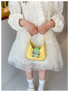 Close-up of yellow and green PU leather bag with silver bow buckle on white star dress