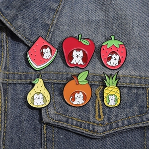 Set of six creative enamel cat fruit pins displayed on a blue denim jacket pocket