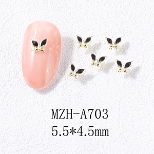 Detailed view of 5.5x4.5mm golden butterfly nail art charms with black enamel finish