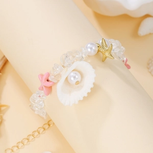 Detail of seashell bracelet with starfish charms and white pearls on display stand
