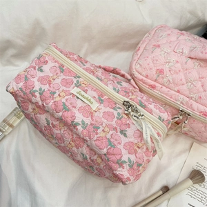 Detail of pink floral quilted cosmetic bags with soft cotton texture and zipper handles