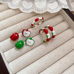 Green and red apple jewelry set with enamel earrings and rings on a velvet display tray