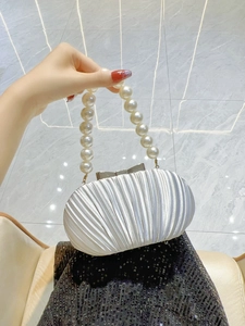 Detail der weißen Abendtasche aus plissiertem Satin mit Perlenriff und Silberrahmen