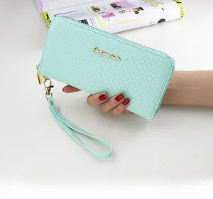 Close-up of mint green leather wallet with gold logo detail and detachable wrist strap