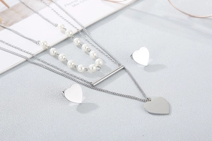 Close-up of triple-layered necklace with white pearls and solid heart stud earrings set