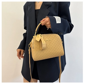 Detail of a beige woven leather handbag showing a top handle and metal logo plaque