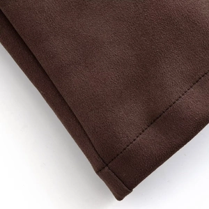 Détail macro du tissu en daim marron avec couture précise à l'aiguille sur le bord