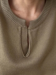 Gros plan du cardigan en maille kaki montrant l'encolure côtelée et la texture du tissu