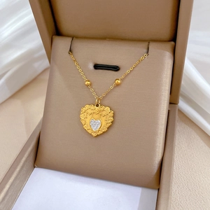 Detail view of a gold heart pendant with MUM engraving and crystal in a brown jewelry box