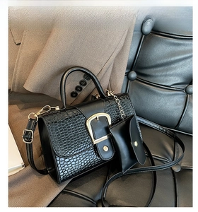 Détail du sac noir à motif crocodile avec boucle dorée et porte-monnaie à chaîne