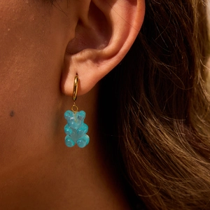 Detailed view of model wearing a blue jelly gummy bear earring with a gold hoop
