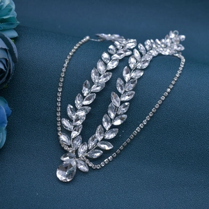 Detailed view of silver rhinestone bridal headpiece with leaf motifs on blue fabric