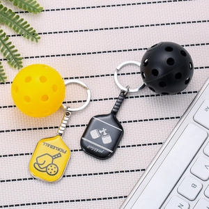 Zinc alloy pickleball keychain set with mini paddles and balls on a textured surface