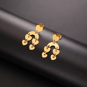 Detailed view of layered golden heart drop earrings on a professional black stand
