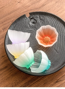 Top view of five lotus-shaped frosted glass tea cups with gradient colors on a tray