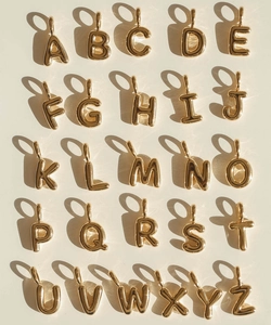 Polished gold initial pendants A-Z arranged in a grid for DIY necklace making