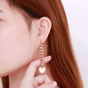 Detail of rose gold stainless steel long tassel earrings with Cuban chain and heart pendant