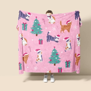 Detail of pink flannel blanket showing cute cats, Christmas trees, and holiday prints