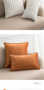 Detailed view of white faux rabbit fur plaid pillow and orange velvet cushion with plush trim