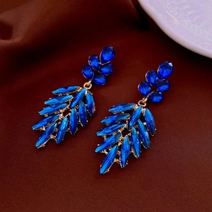 Close-up of deep blue crystal leaf tassels with gold settings on vintage earrings