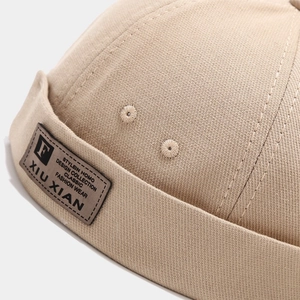Détail du bonnet Miki kaki avec écusson en cuir marron, lettre F et coutures de précision