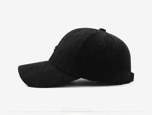 Detail view of black herringbone wool baseball cap with small gold metal side logo