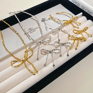 Collier élégant avec nœud papillon en or et argent présenté sur un coffret à bijoux en velours