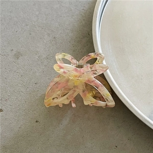 Detailed top view of a small acetate butterfly hair claw with floral oil painting patterns