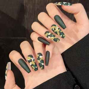 Matte armee-grüne und Camouflage-Kunstnägel in langer Sargform an der Hand