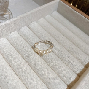 Détail d'une bague minimaliste avec perles baroques et métal argenté texturé dans une boîte