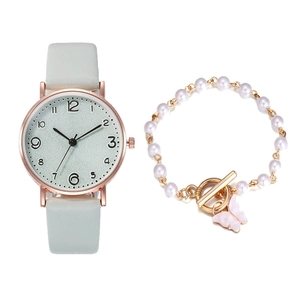 Detailed view of women's gold watch with blue leather strap and pearl butterfly bracelet