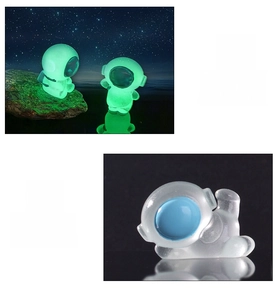 Detailed comparison of glowing resin astronaut miniatures in light and dark environments