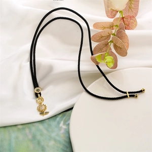 Detail of sunflower pendant with clear crystals and green leaf on black cord necklace