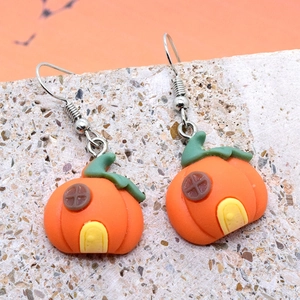 Handcrafted pumpkin house resin earrings with green stems on stone surface