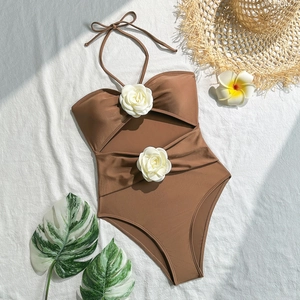 Close-up of brown halter swimsuit featuring decorative white 3D flowers and drawstrings