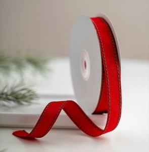 Detail of red grosgrain ribbon with green dashed stitching for Christmas gift wrapping