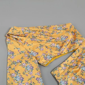 Close-up of yellow floral satin fabric with vibrant purple and blue patterns